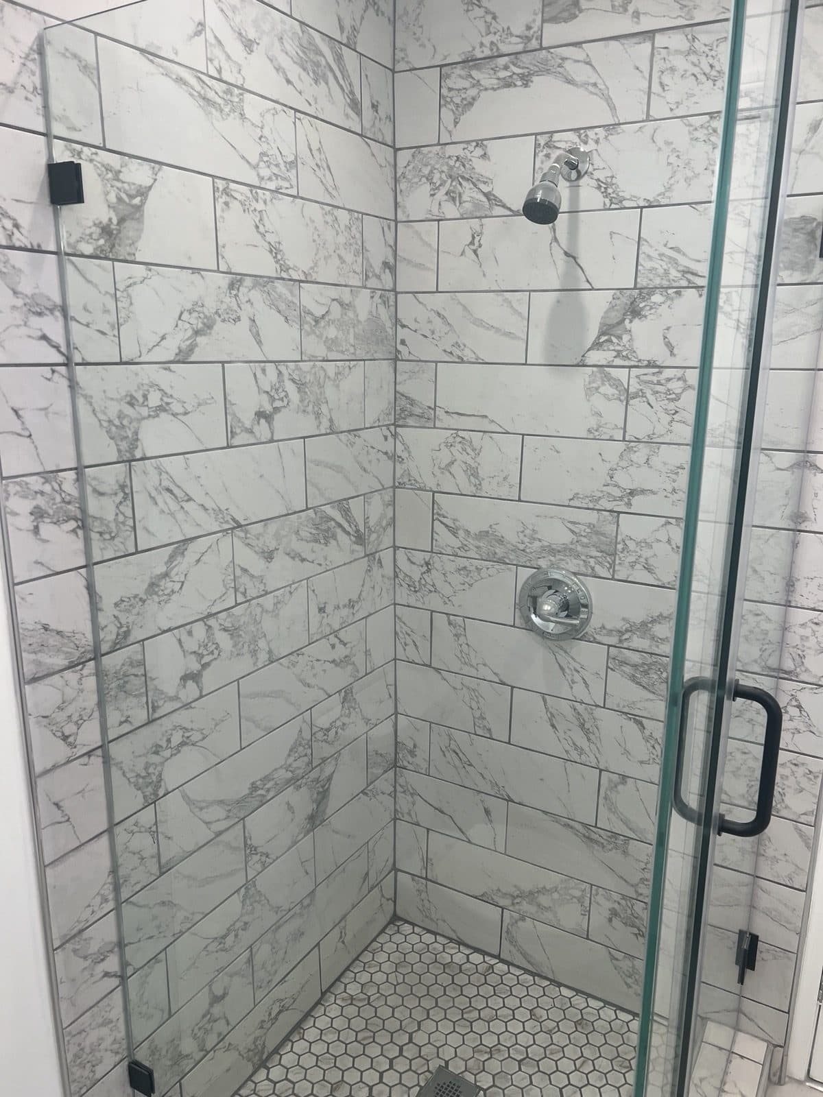 Tiled shower with a glass enclosure and hex tile floor