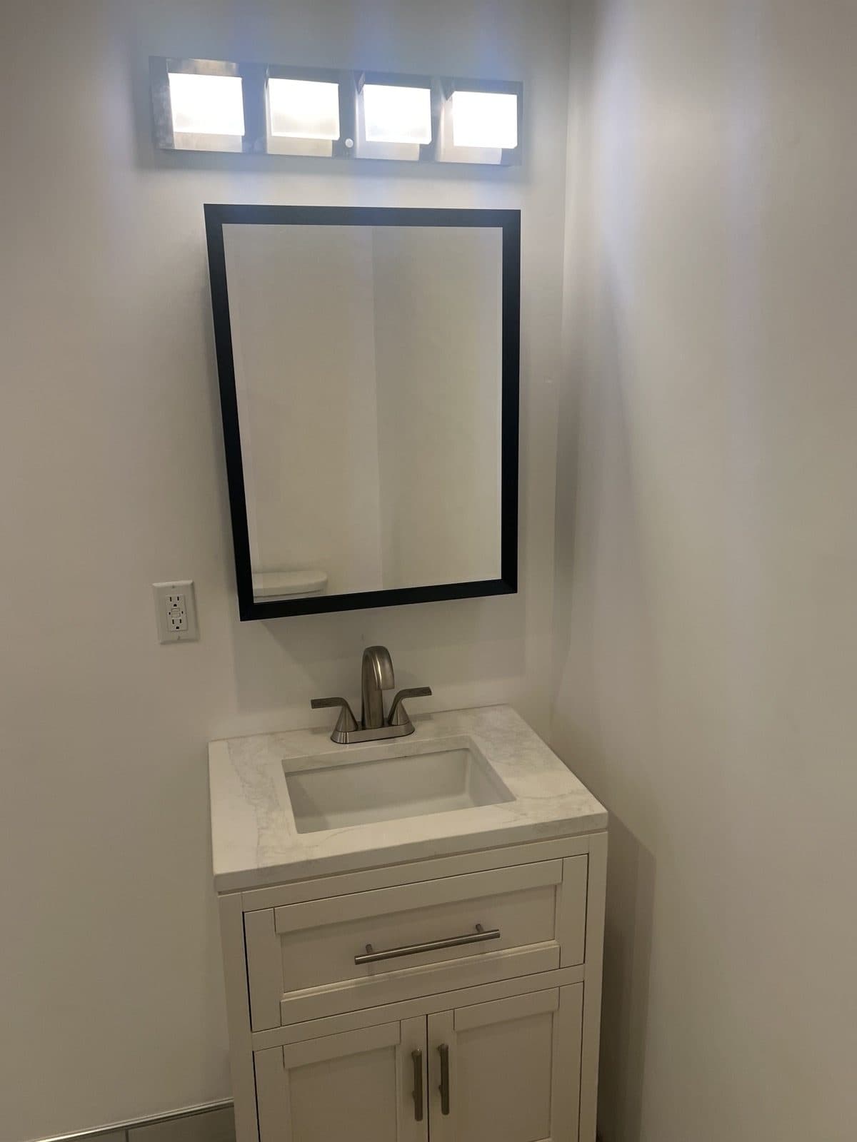 Finished bathroom vanity with a framed mirror and clerestory windows
