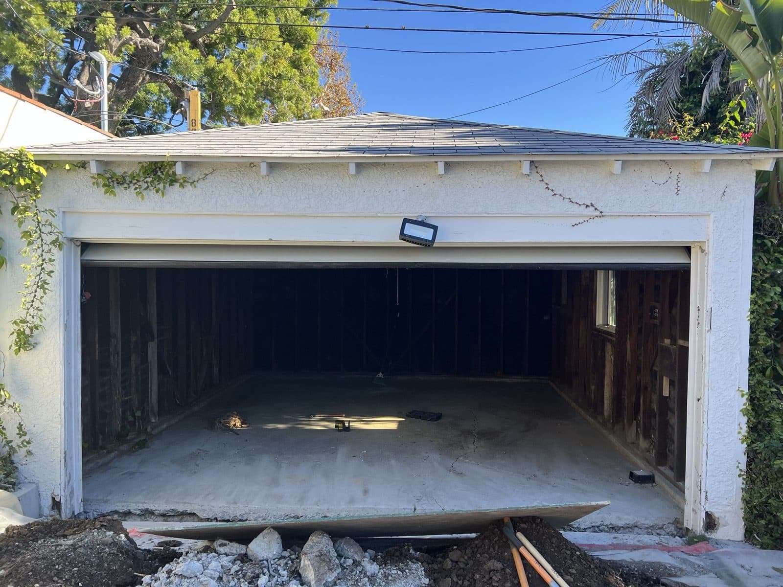 The original detached garage before work started, with a dirt floor edge and open bay