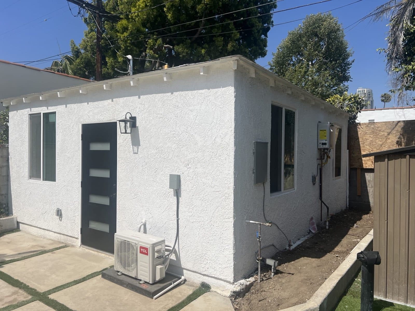 Finished ADU exterior from the side, with the mini split condenser and utility connections
