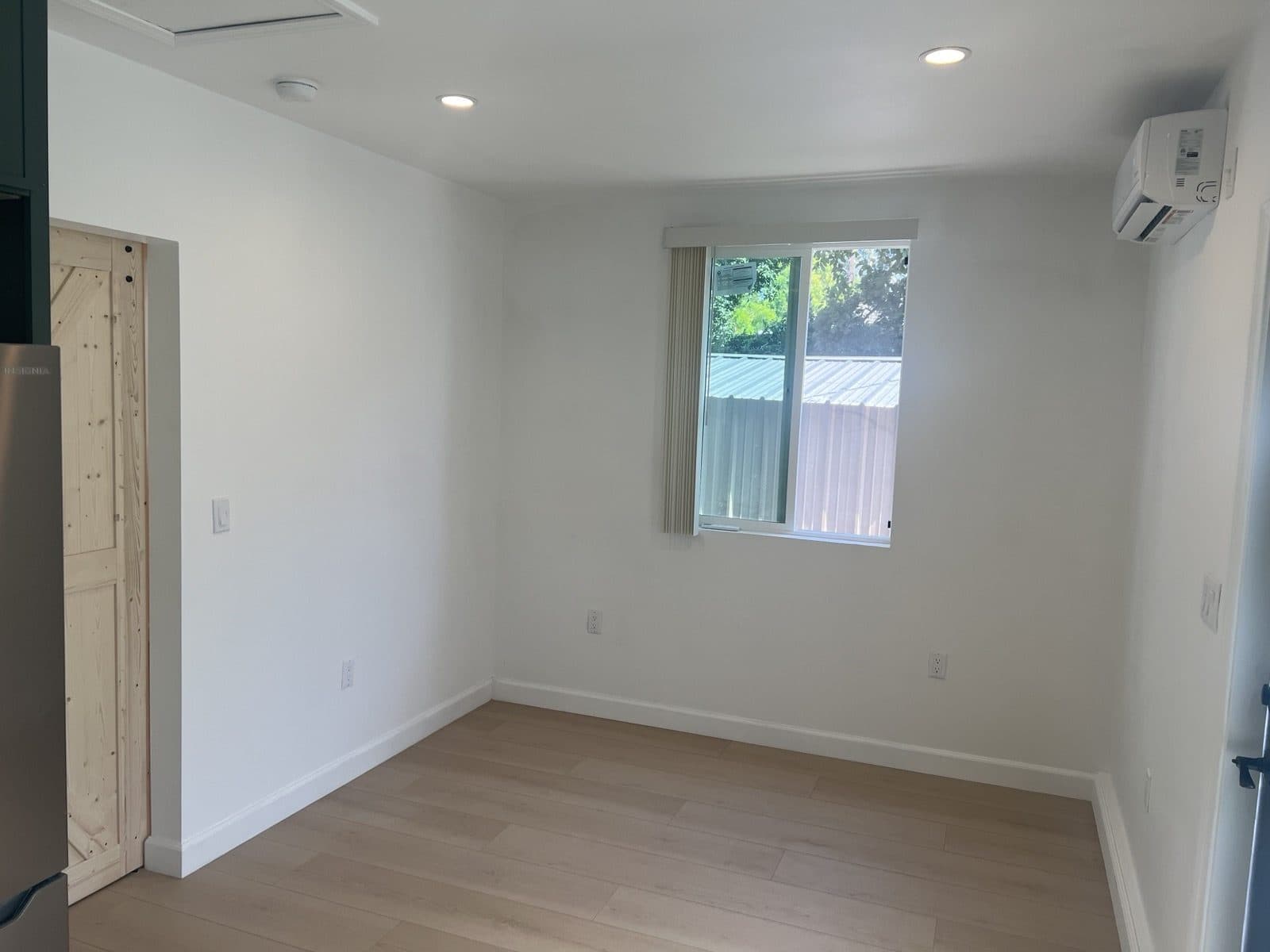 Finished living area with light wood floors and a mini split unit