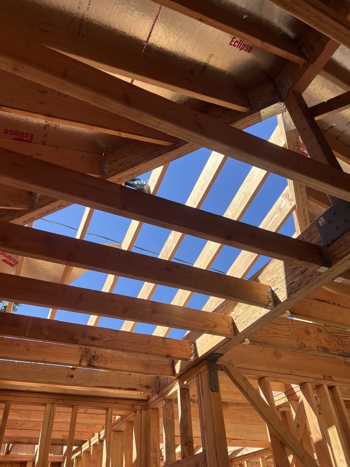 Roof framing seen from inside, with rafters and sheathing going on